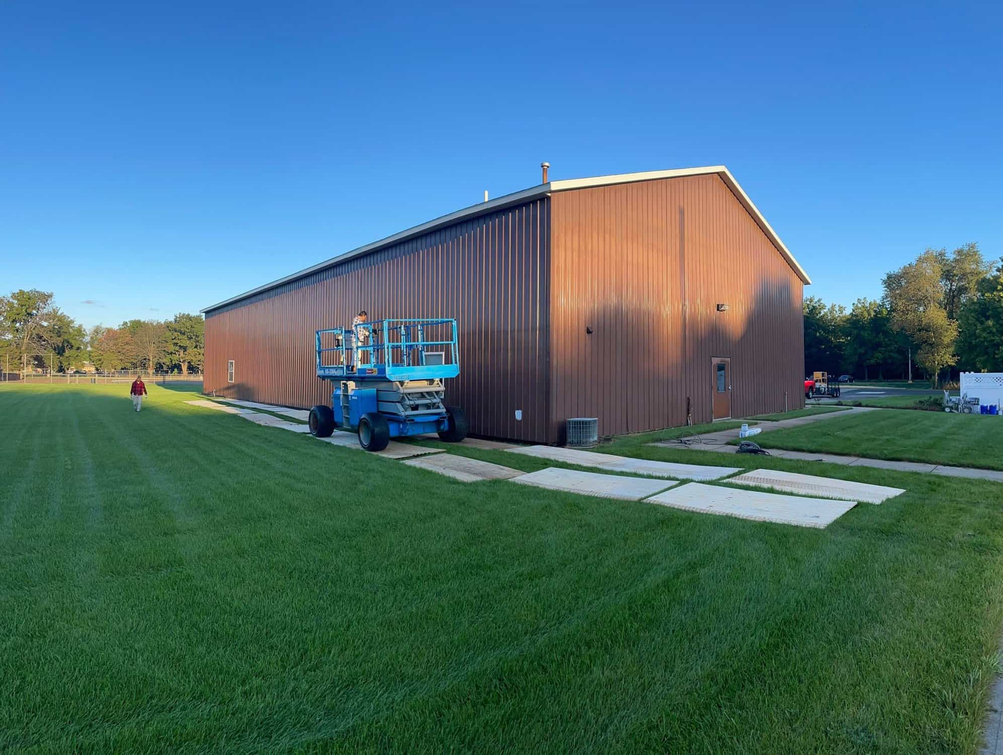 H&H crew painting an industrial building from a lift